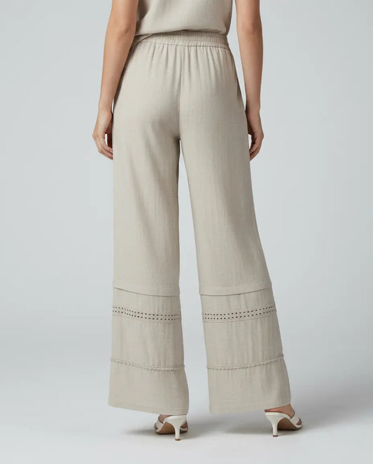 Beige wide leg trousers with lace-trimmed lower panels and elastic waistband