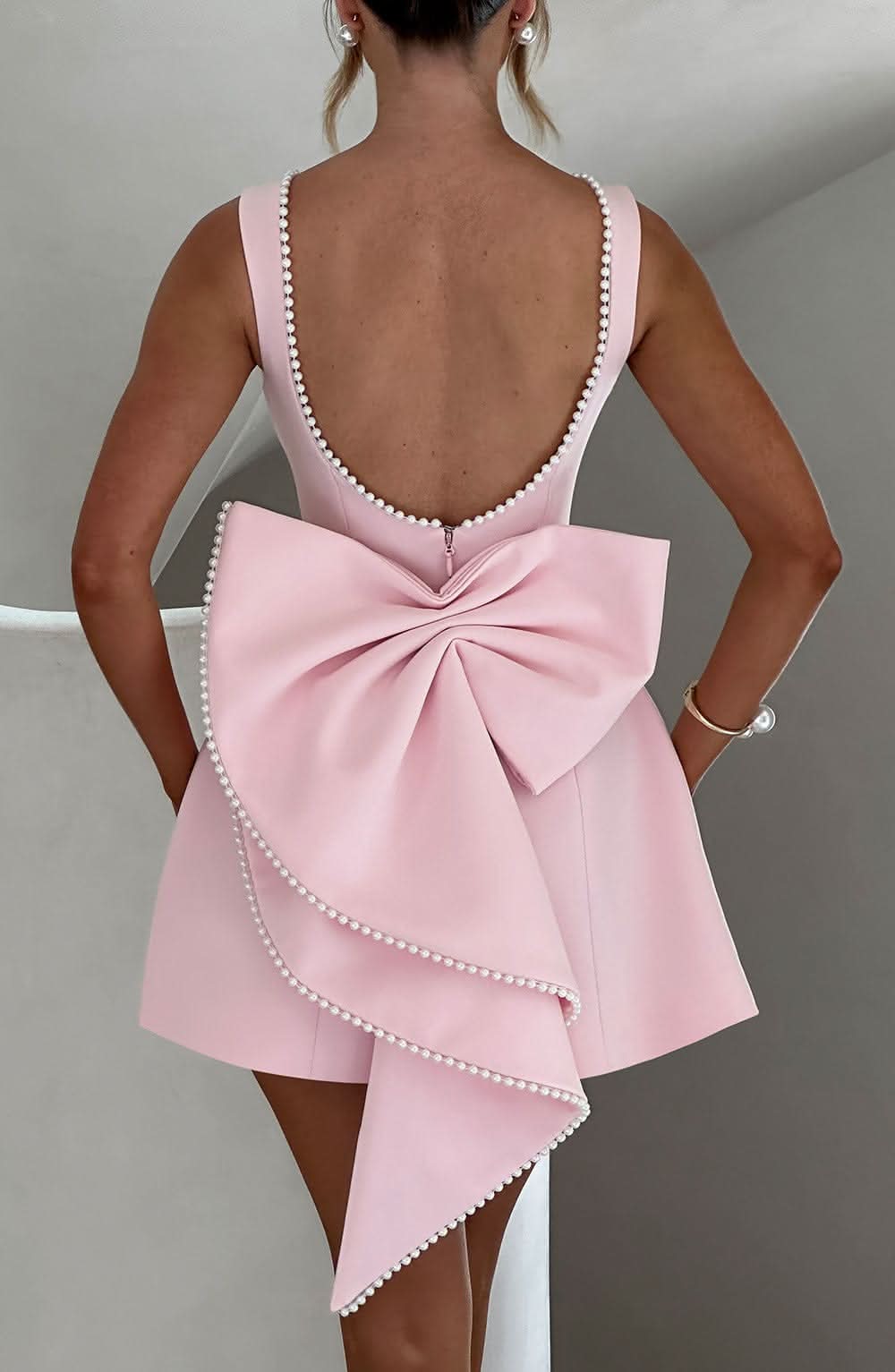 Pink A-line mini dress with bow back and pearl-trim strappy back
