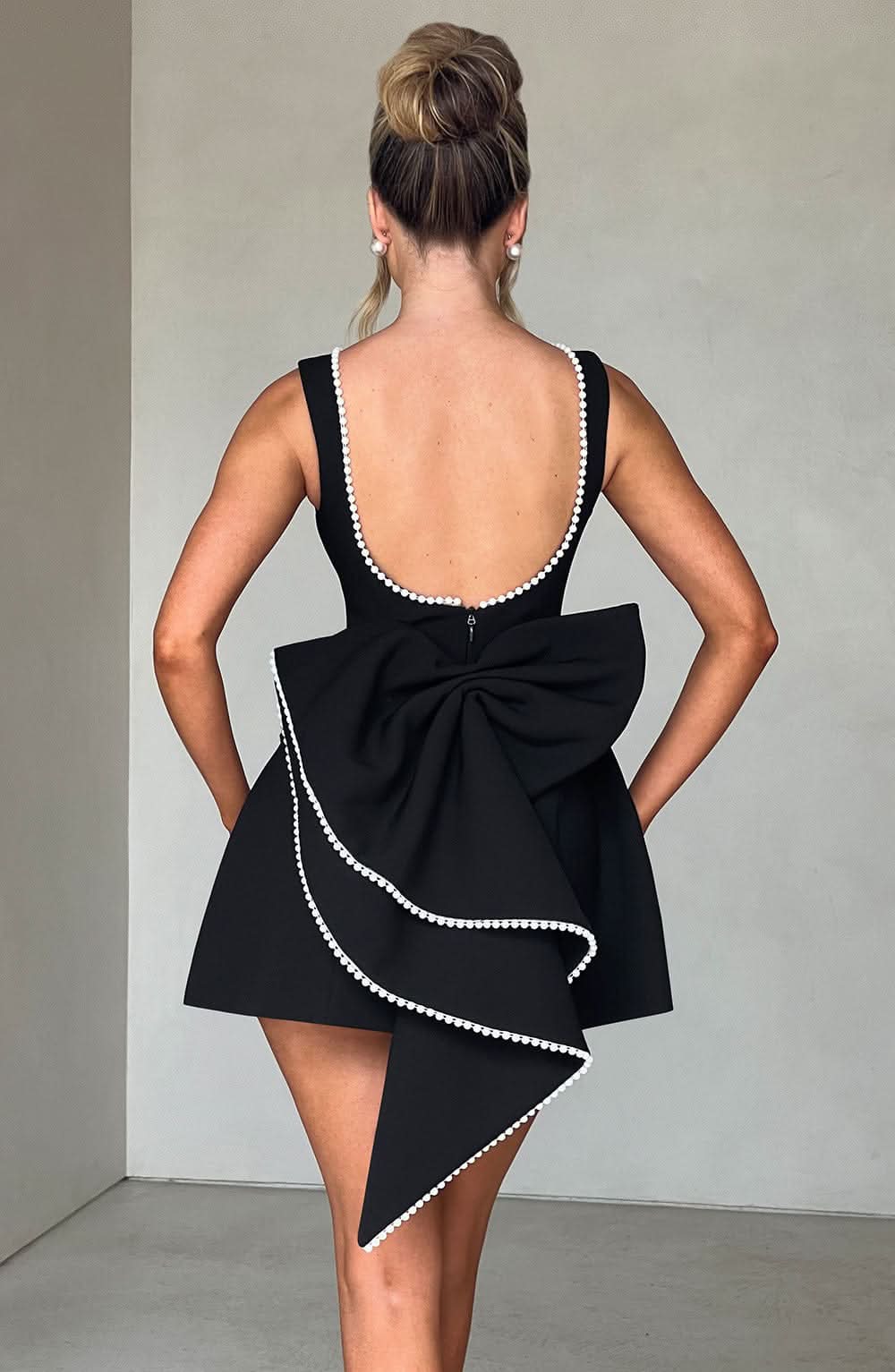 Black A-line mini dress with bow back and pearl-trim open back straps