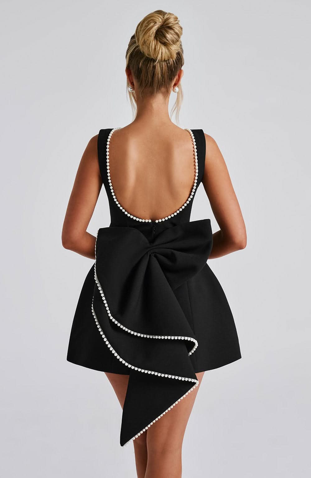 Black A-line mini dress with bow back and rhinestone-trim straps, back view