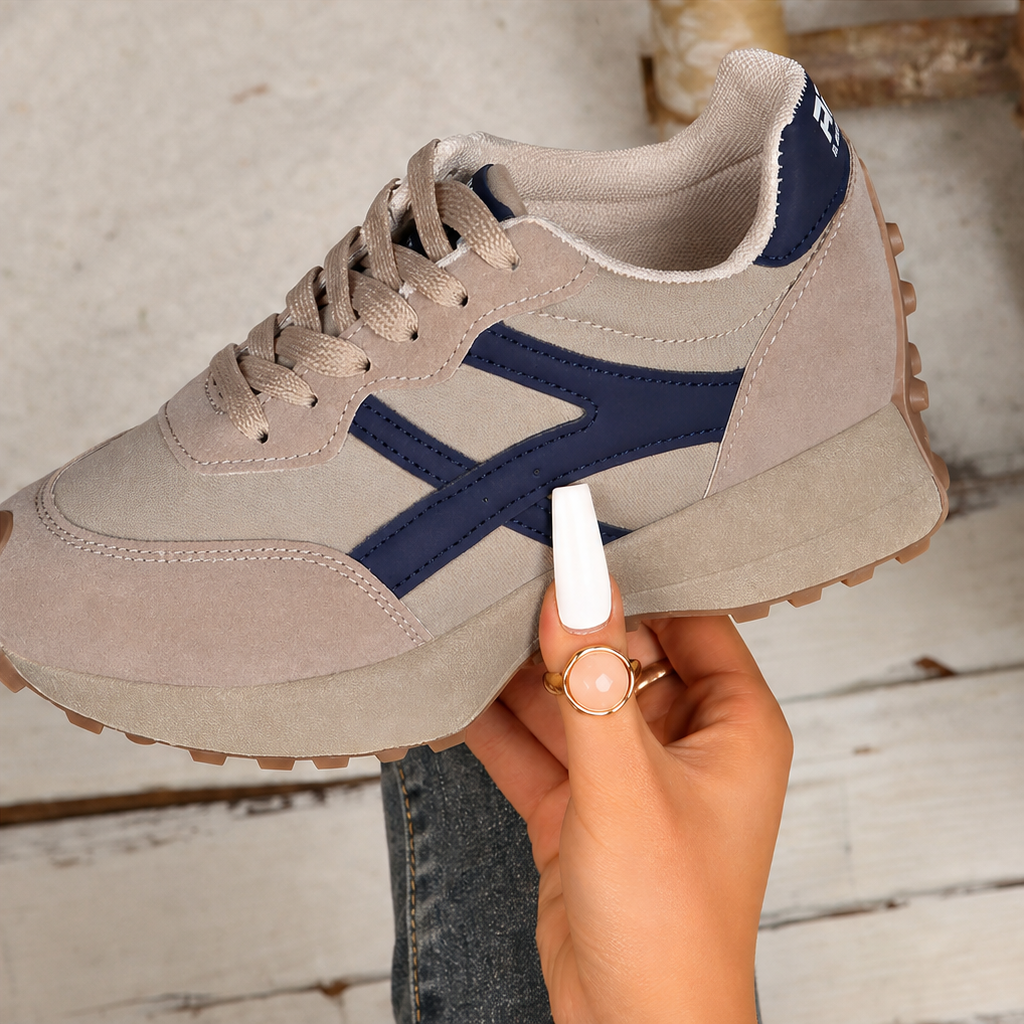 Beige and navy platform sneakers held up, showing lace-up and chunky sole.