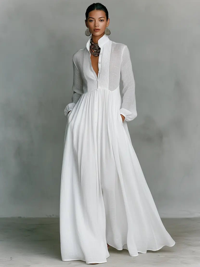 White maxi dress with long sleeves, gathered waist, and flowing maxi skirt