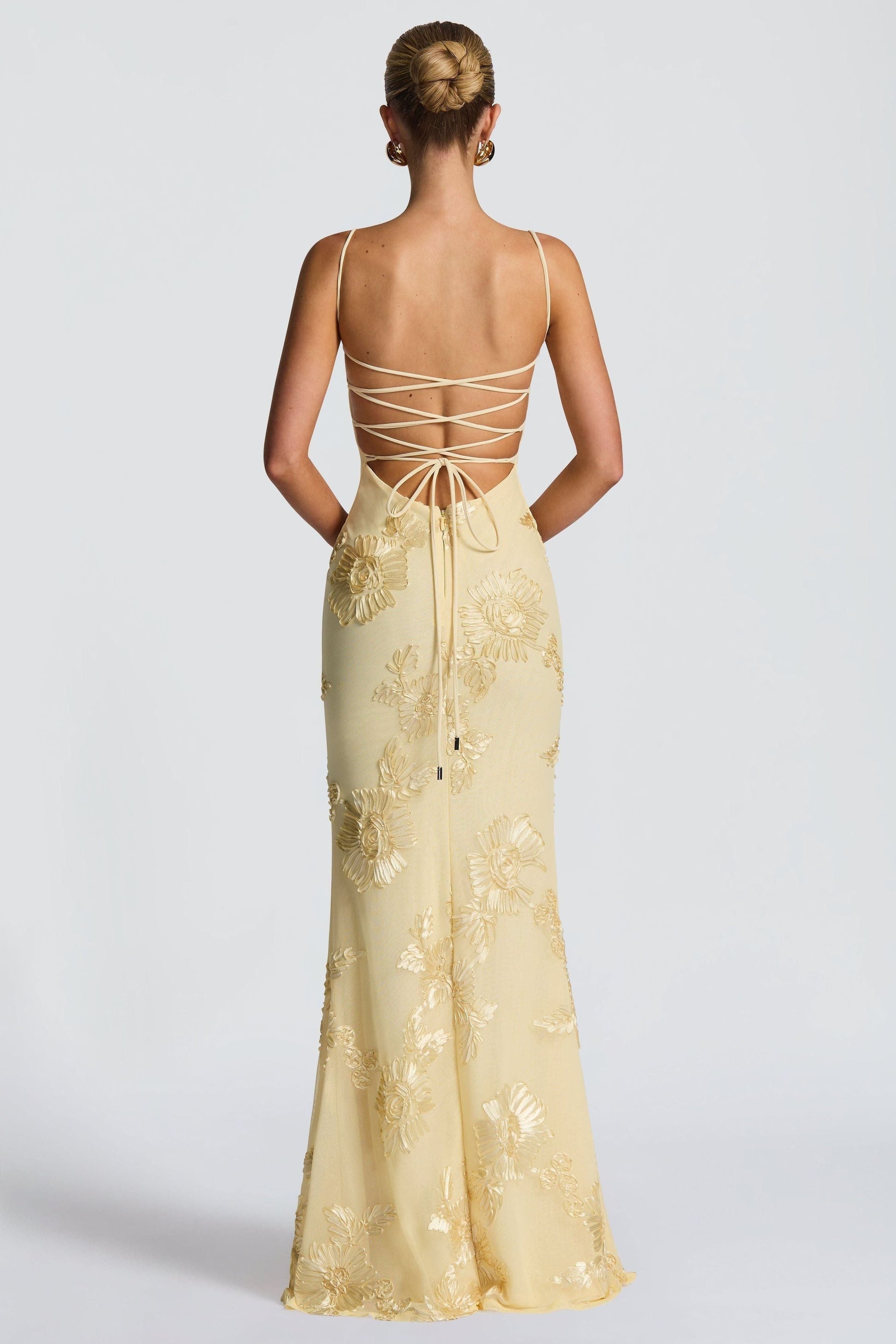 Yellow bustier maxi dress back view with crisscross lace-up straps and floral applique