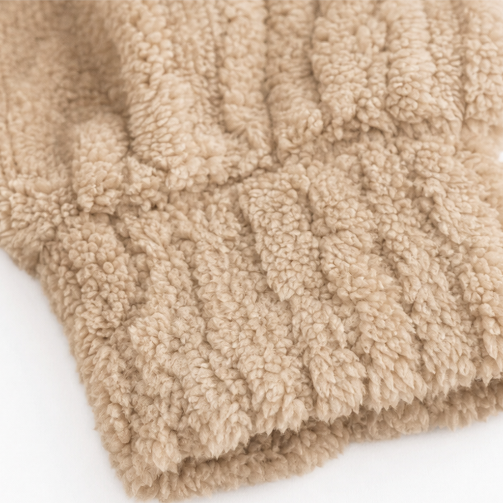 Close-up of tan ribbed hem on fuzzy cable-knit quarter-zip pullover