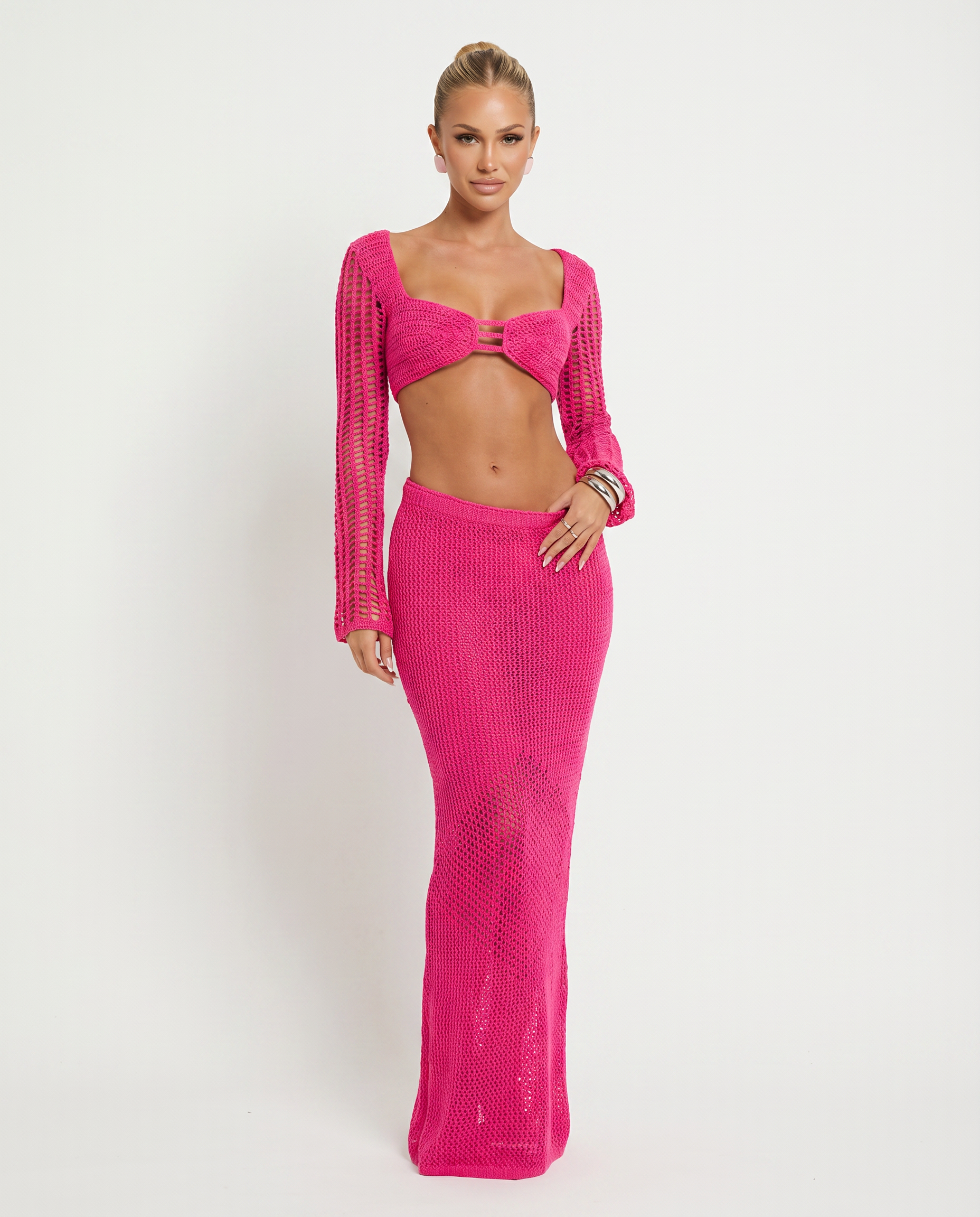 Pink crochet knit two-piece set with long sleeves, bandeau crop top and maxi skirt.