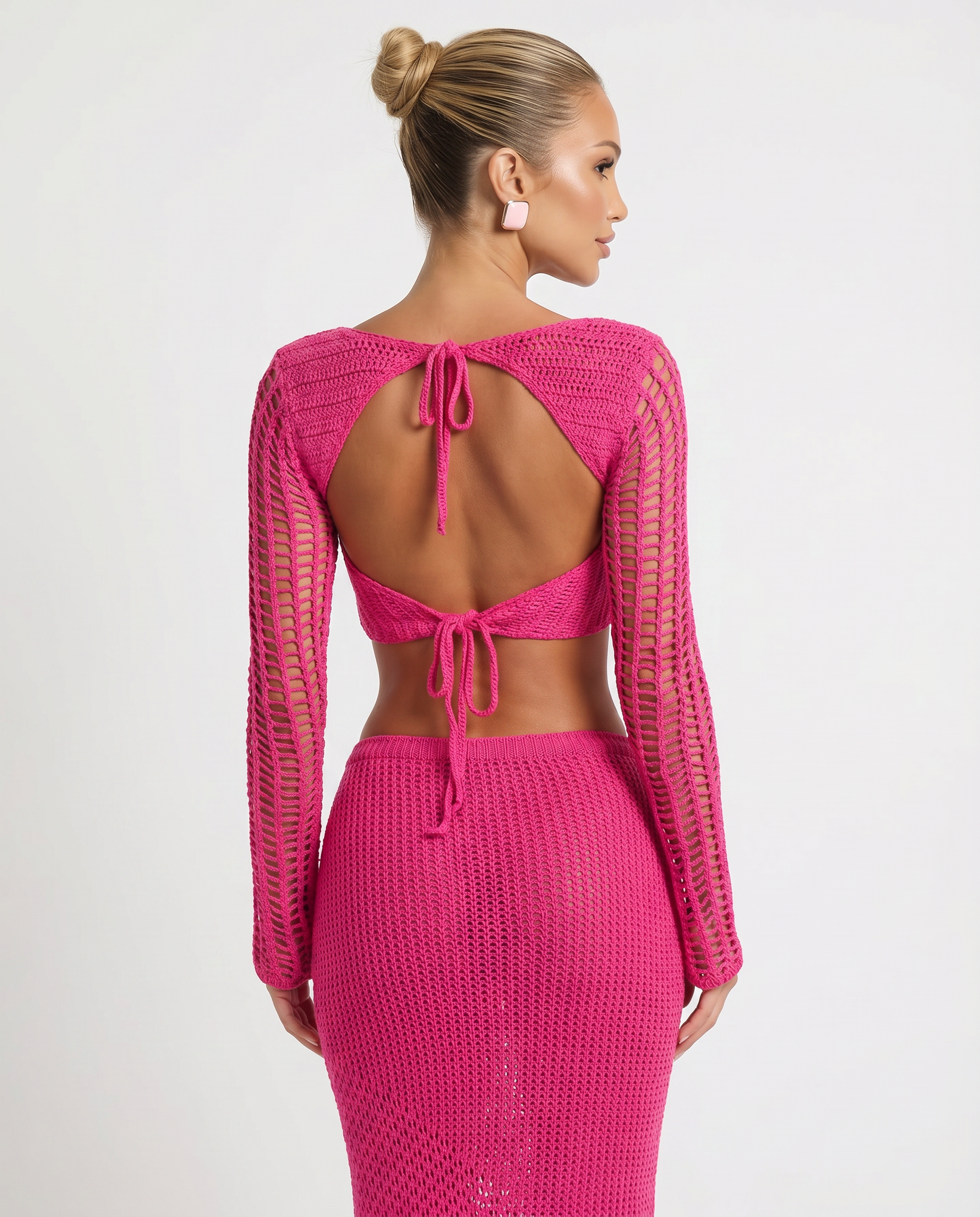 Pink crochet knit two-piece set, back-tie crop top and long-sleeve maxi skirt.