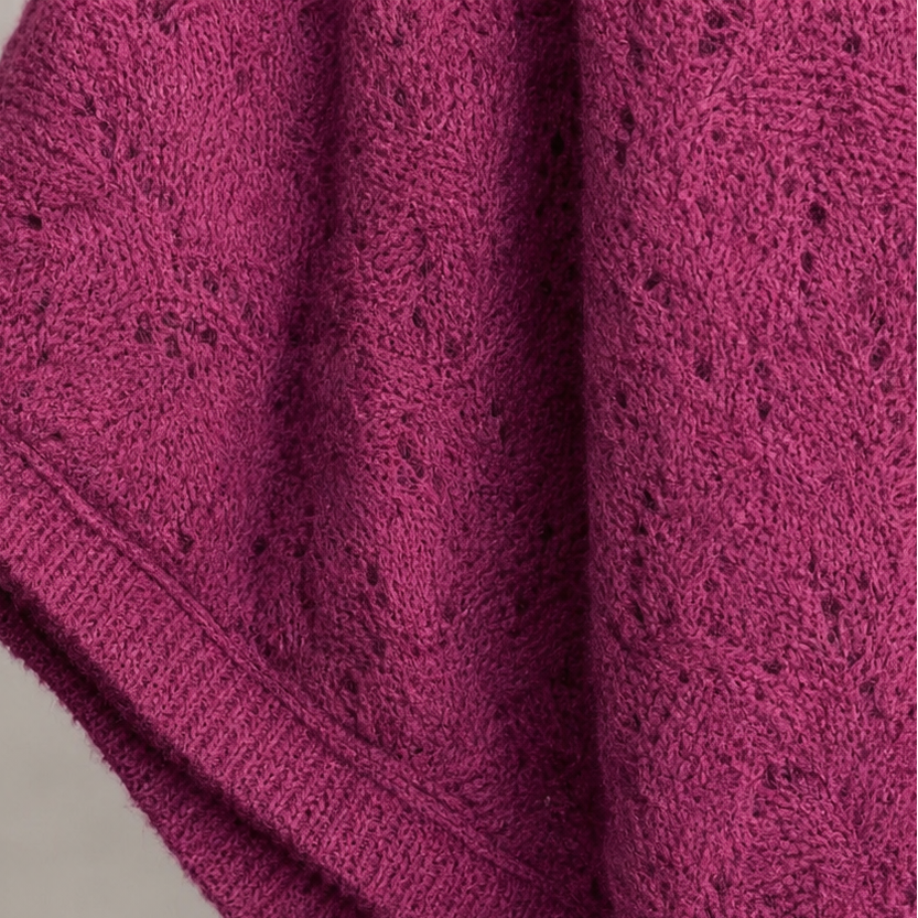 Close-up of purplish-red knit sleeve cuff and textured openwork pattern