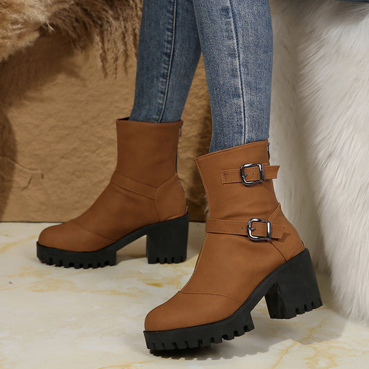 Brown ankle boots with two buckles, thick block heel and treaded lug sole.