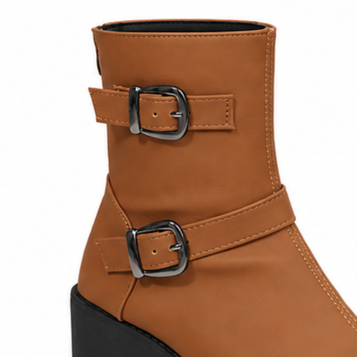 Brown ankle boots with double side buckles and thick black lug sole.