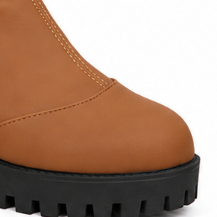 Brown ankle boot toe with stitched seams and chunky black lug sole.