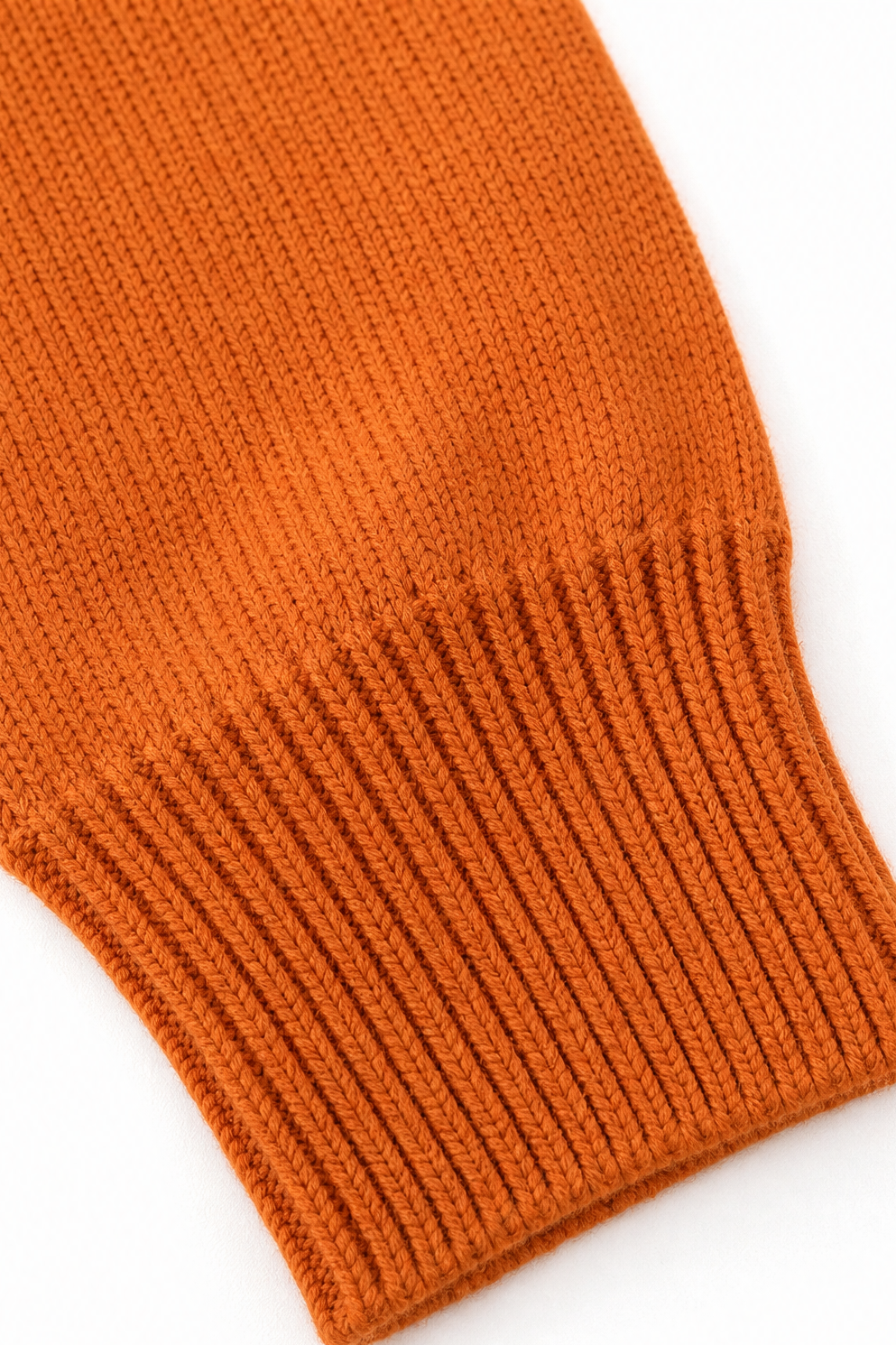 Close-up of orange knit pullover ribbed hem texture