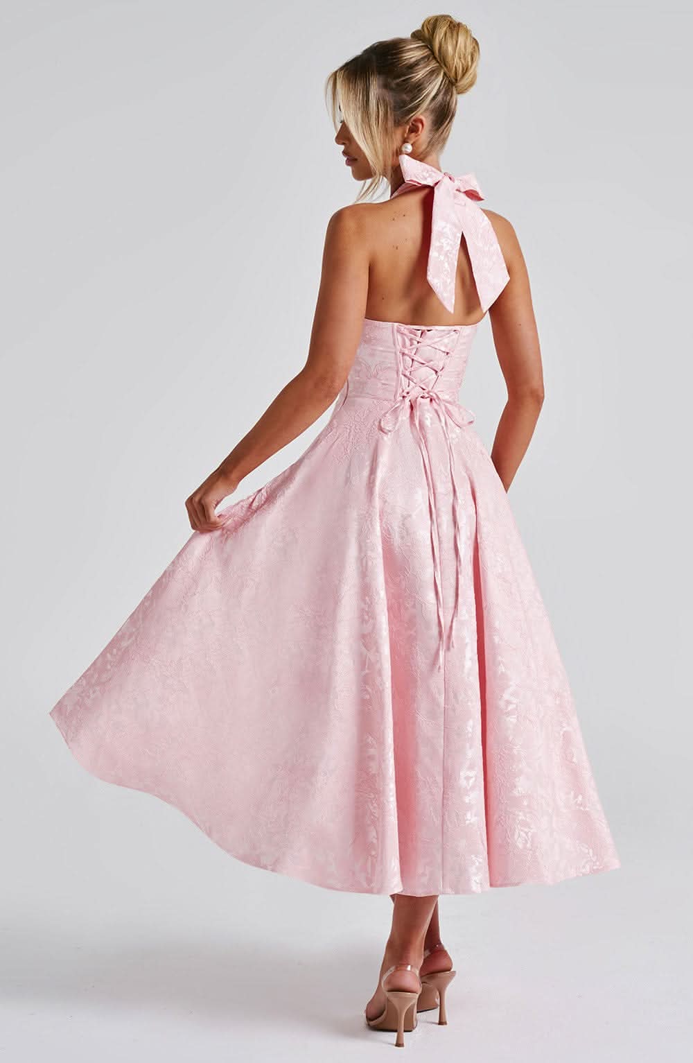Pink halter midi dress, open-back tie bow and gathered waist with jacquard flare