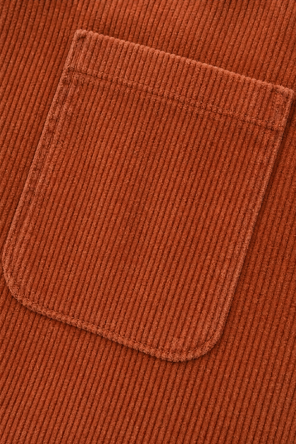 Rust-orange corduroy-look jacket pocket with flap detail close-up
