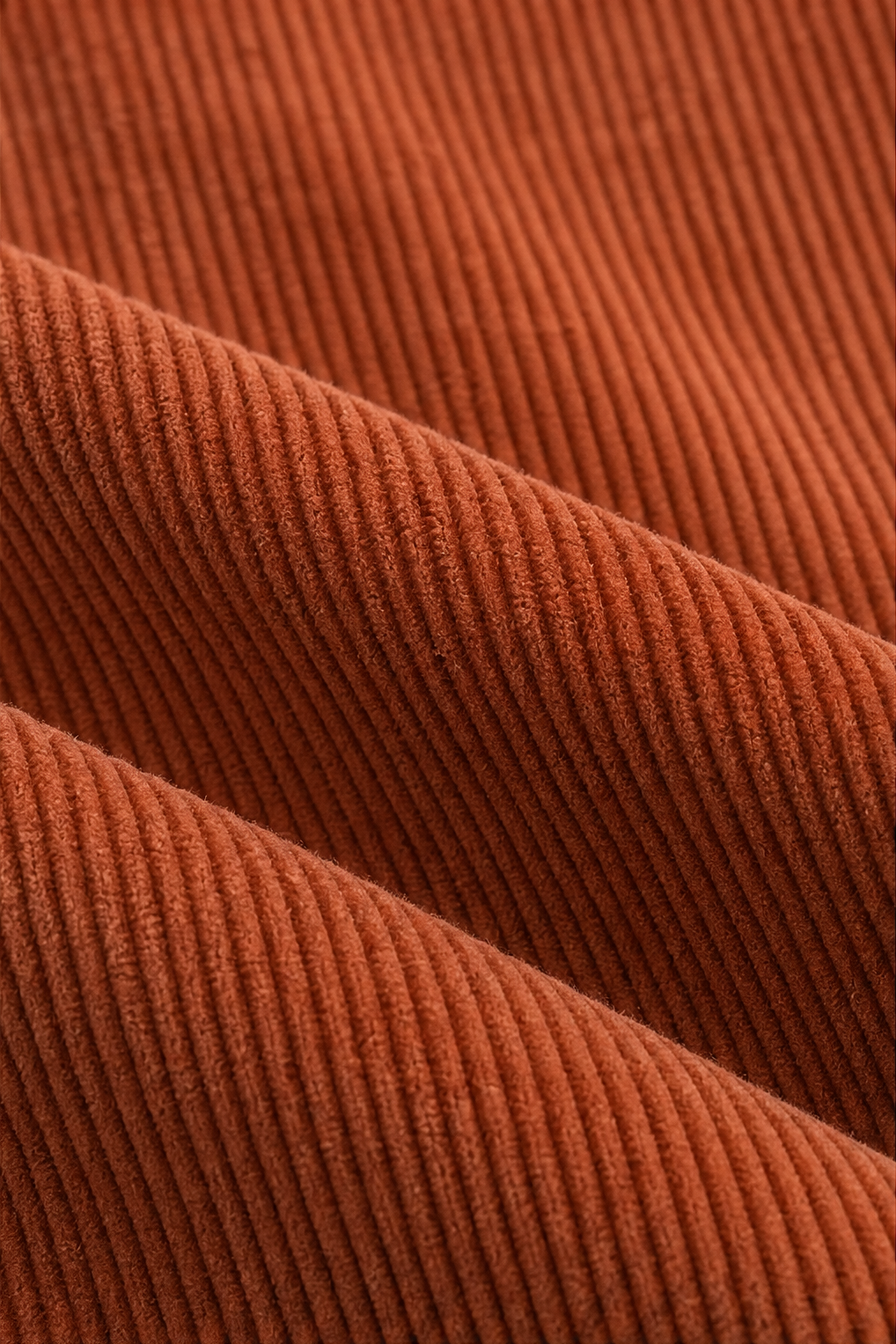 Rust-orange corduroy-look ridged texture on jacket sleeve close-up