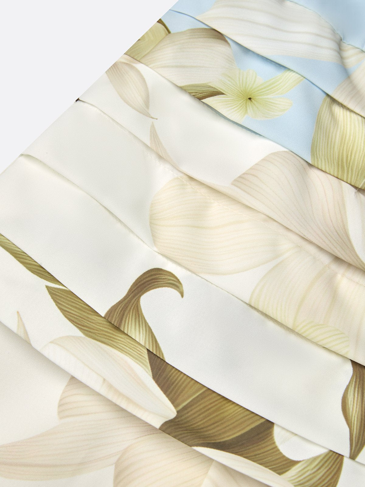 Close-up of cream and pale green floral fabric with pleated band and smooth drape.
