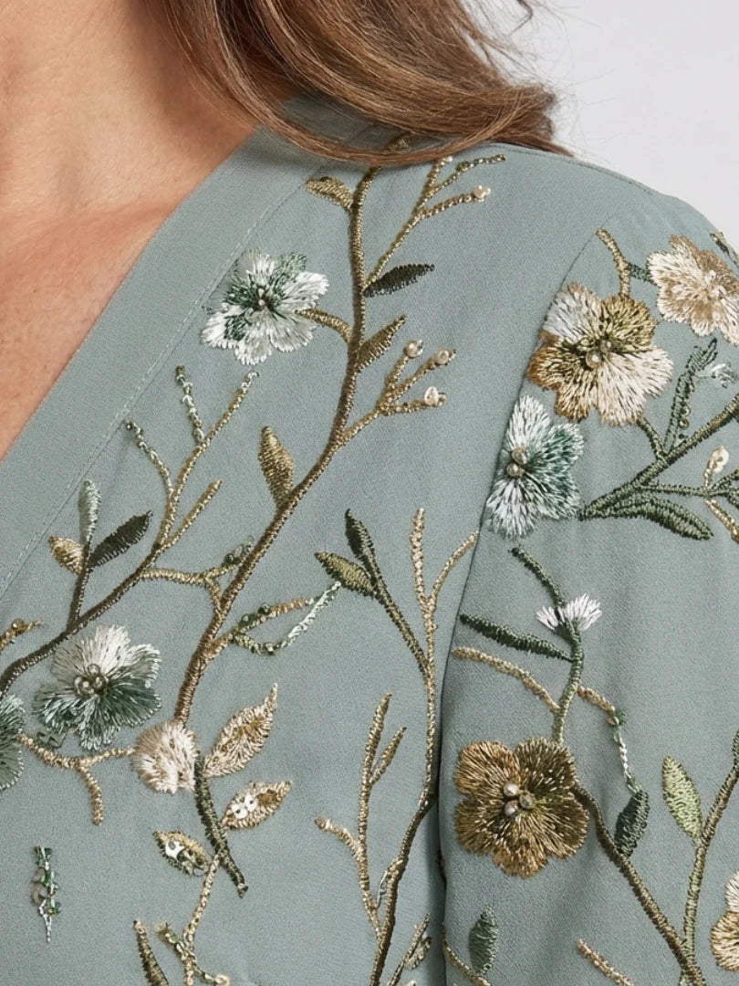 Close-up of sage green floral embroidery on the dress back and shoulder yoke