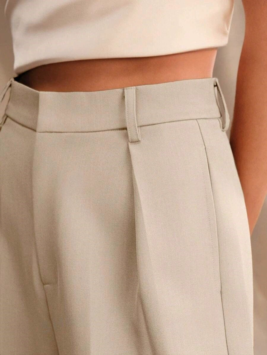 Beige trousers waistband close-up with belt loops and front pleats