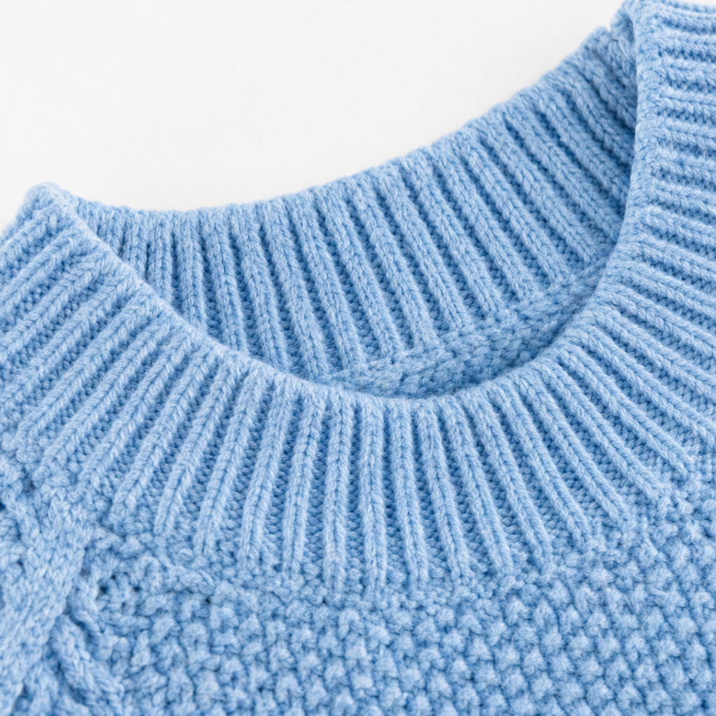 Close-up of light blue ribbed crew neckline on cable-knit sweater