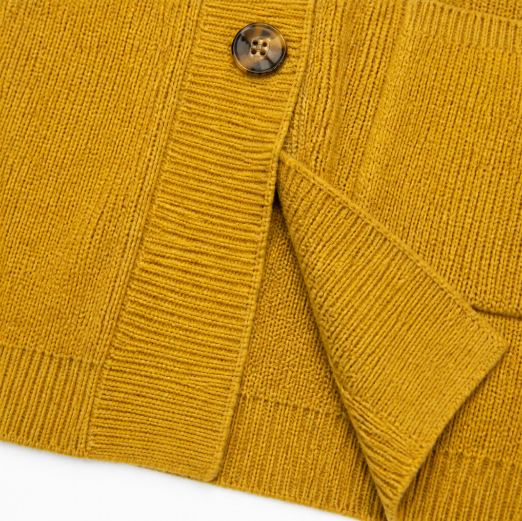 Close-up of yellow ribbed knit cardigan fabric, button and placket