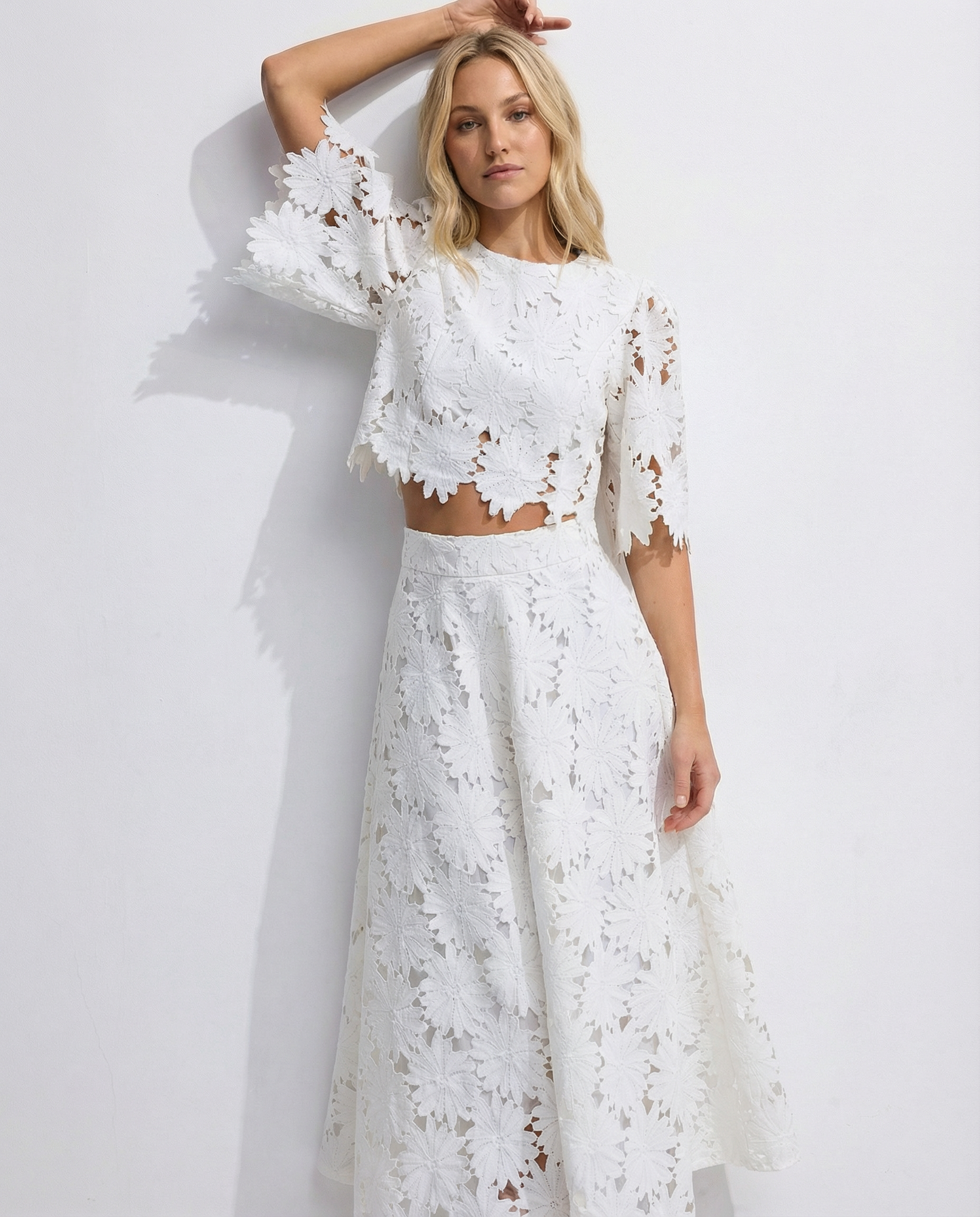 White lace crop top and maxi skirt set with floral embroidery, one arm raised
