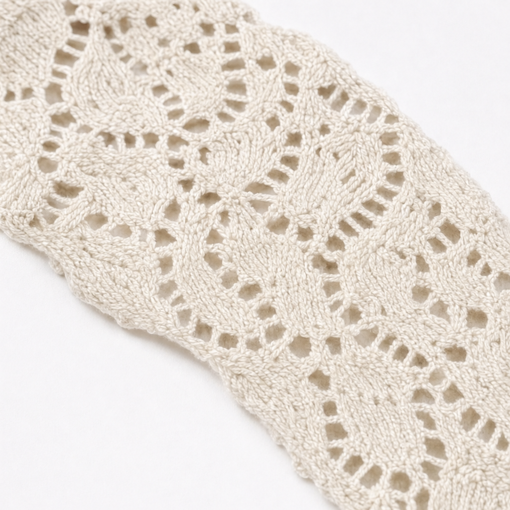 Close-up of cream lace shoulder panel with openwork crochet pattern on knit top.