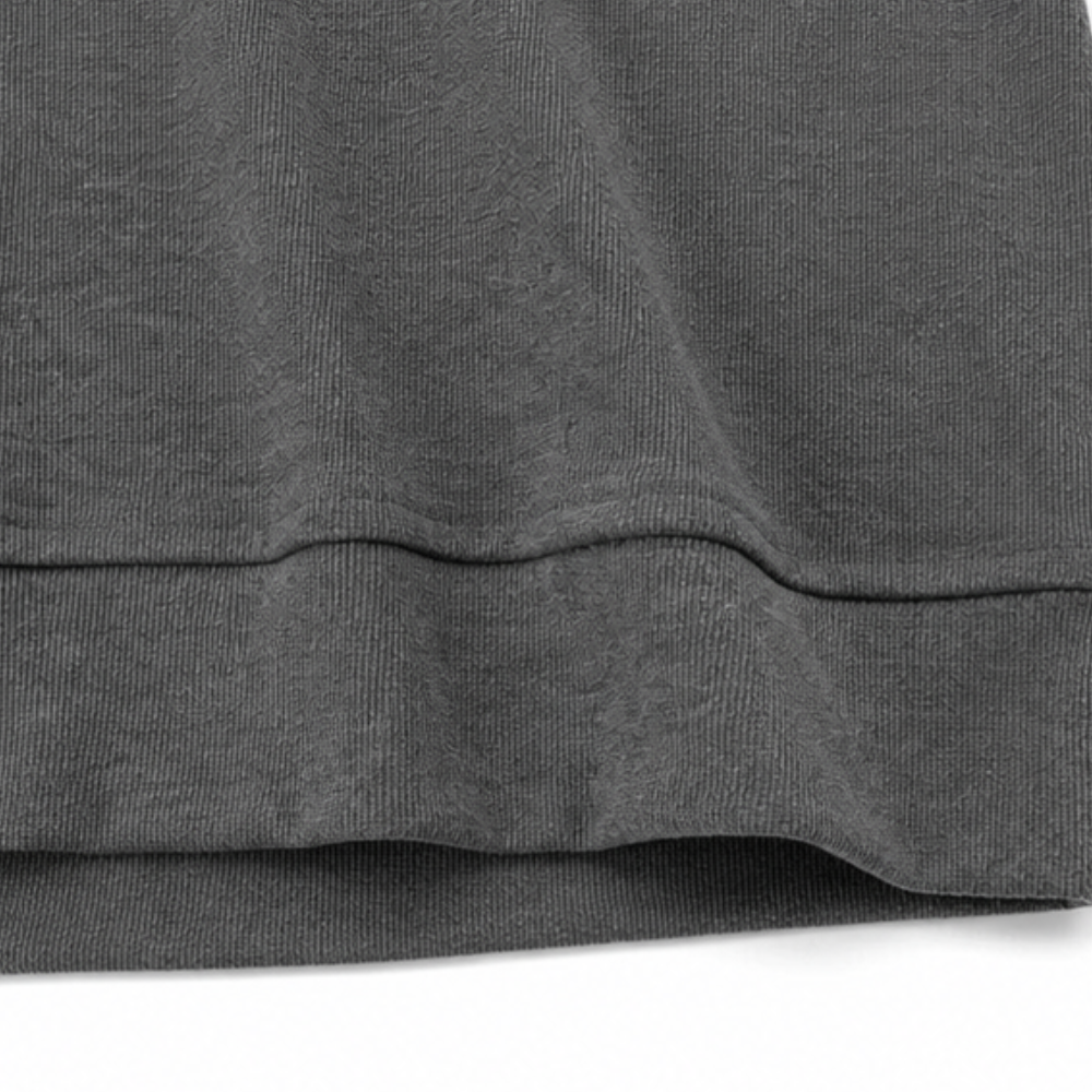 Close-up of dark grey waffle knit fabric hem detail on a hooded henley hoodie