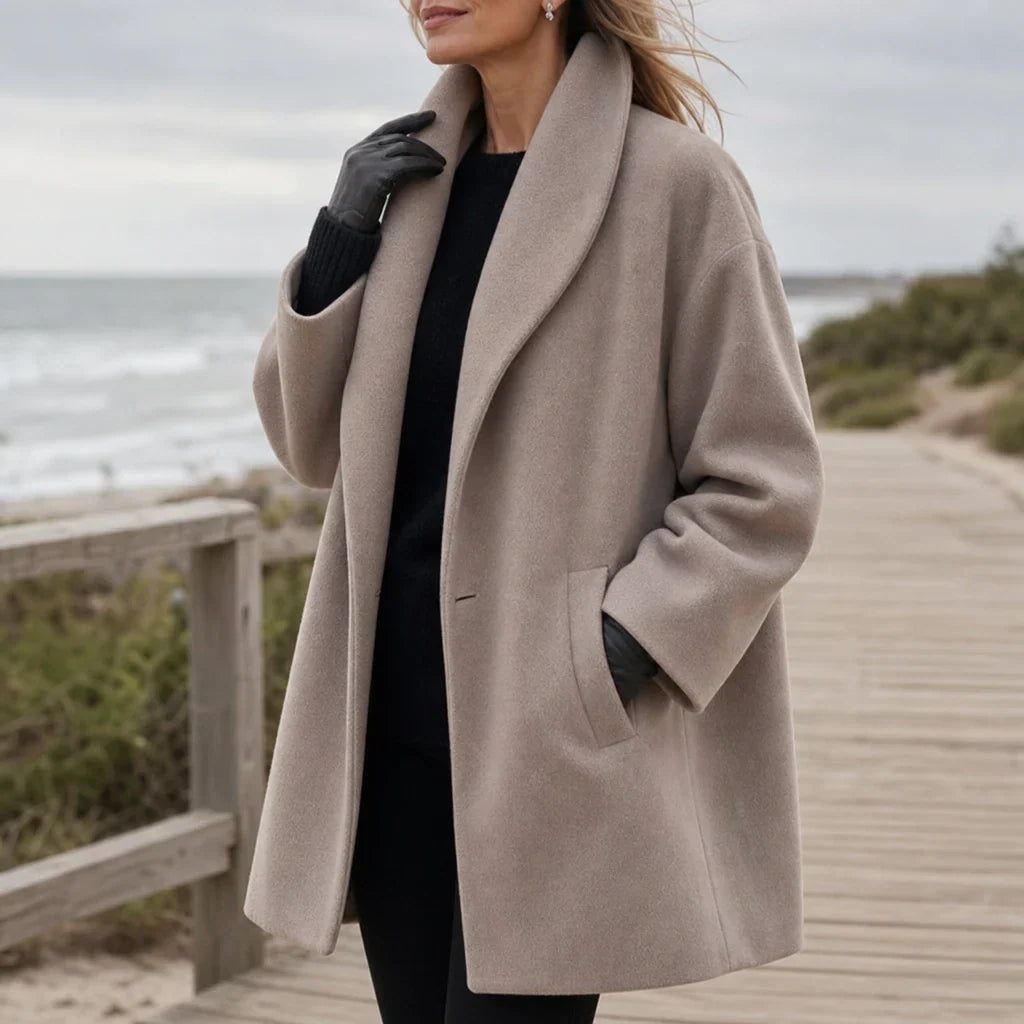 Taupe oversized coat with wide lapels, long sleeves, and a front welt pocket.