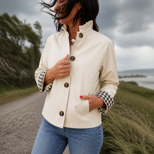 Beige short trench coat with ruffle neck and plaid cuff trim over the sleeve.