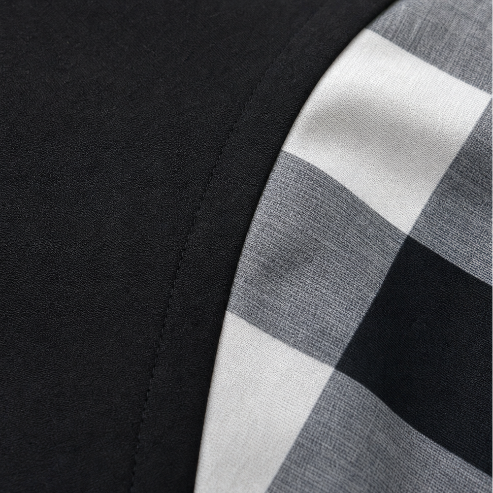 Close-up of black fabric edge with stitched seam next to plaid panel in black and gray