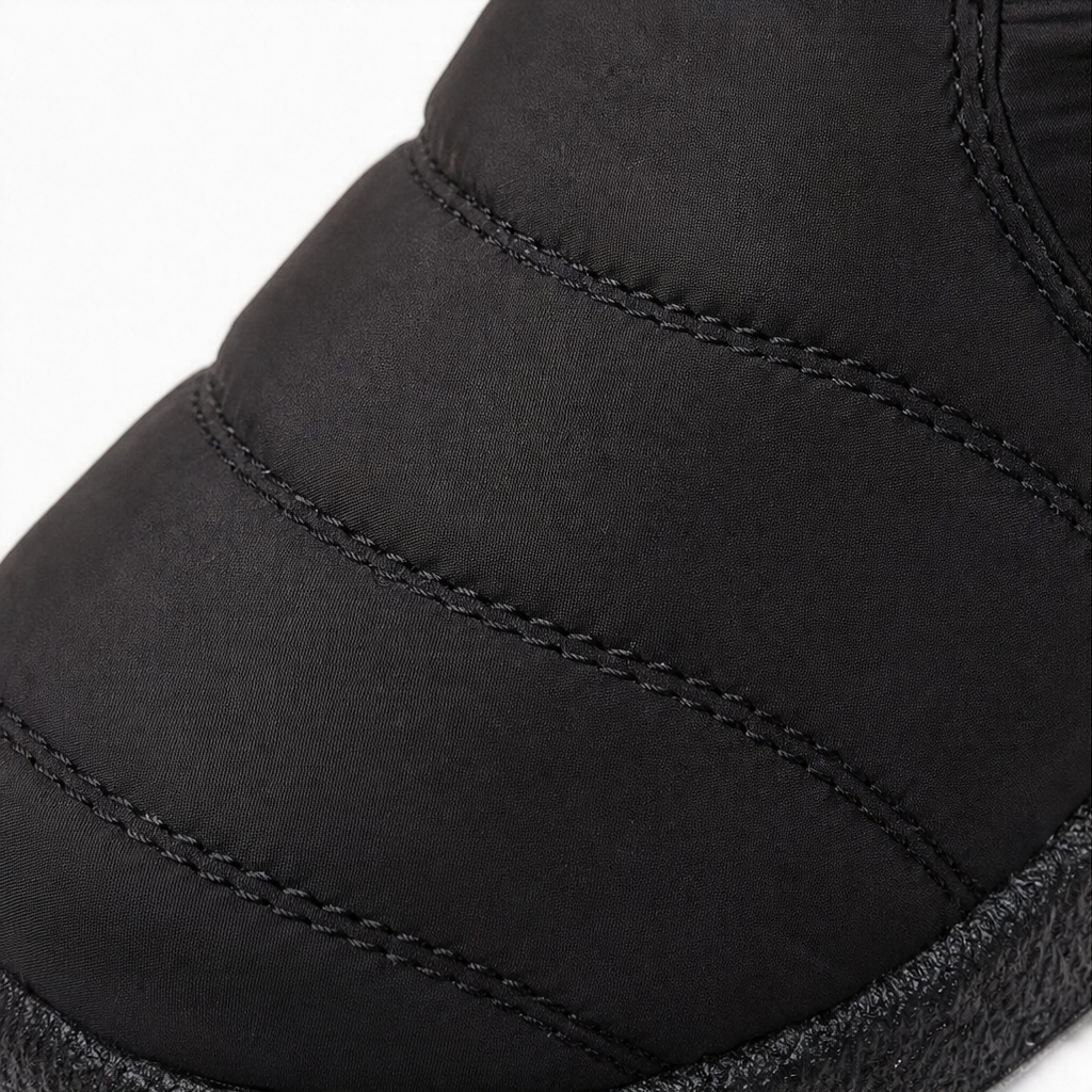 Close-up of black stitched boot upper with padded panels and textured trim.