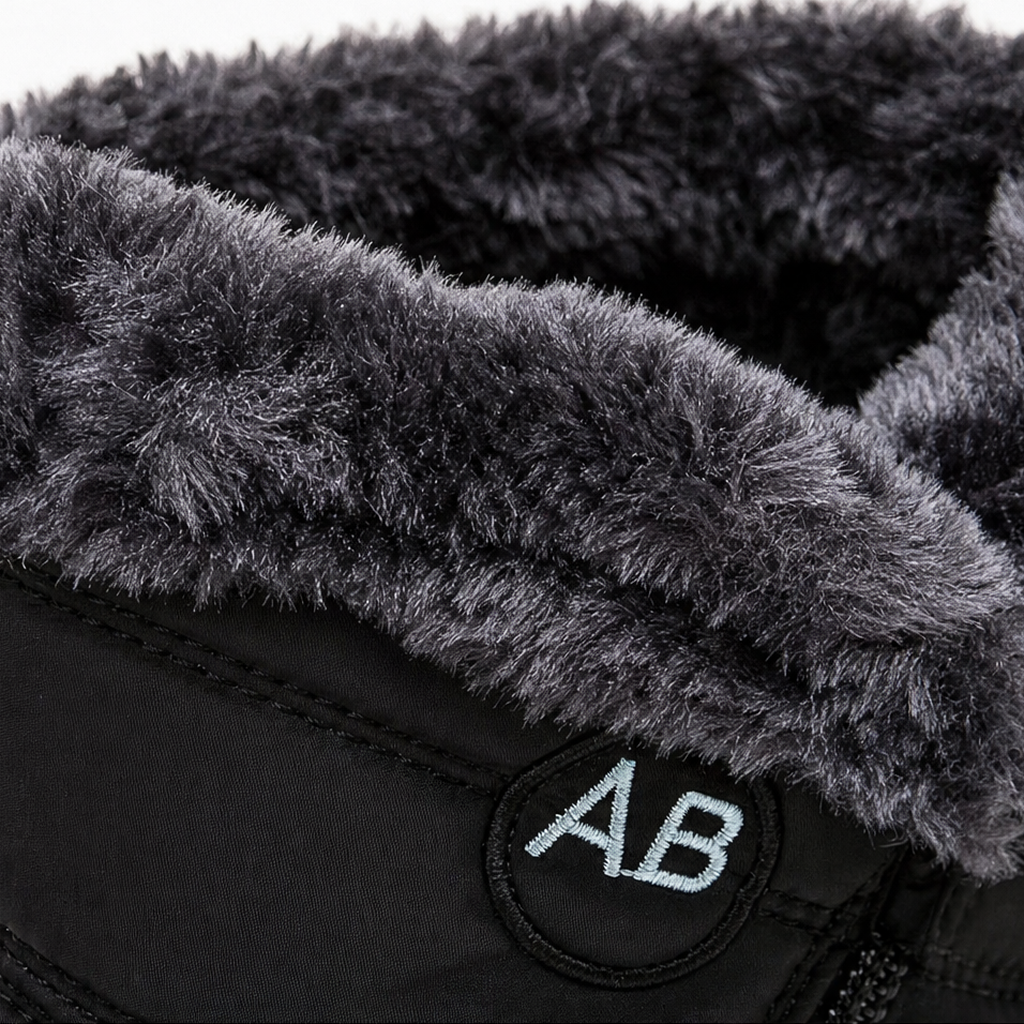 Faux-fur cuff close-up on black ankle boot with AB logo patch.