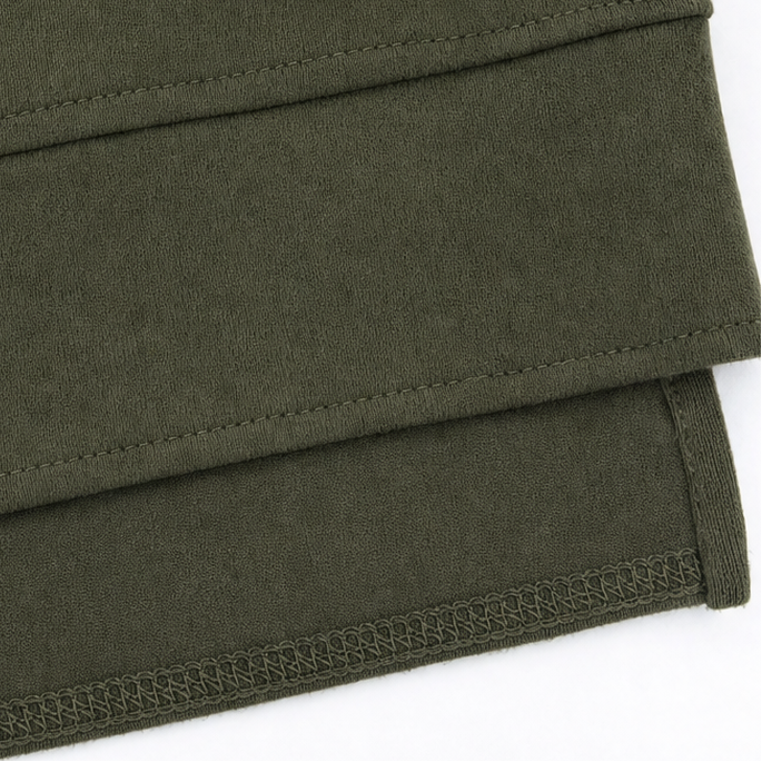 Army green tunic hem close-up showing stitched edge and overlock seam