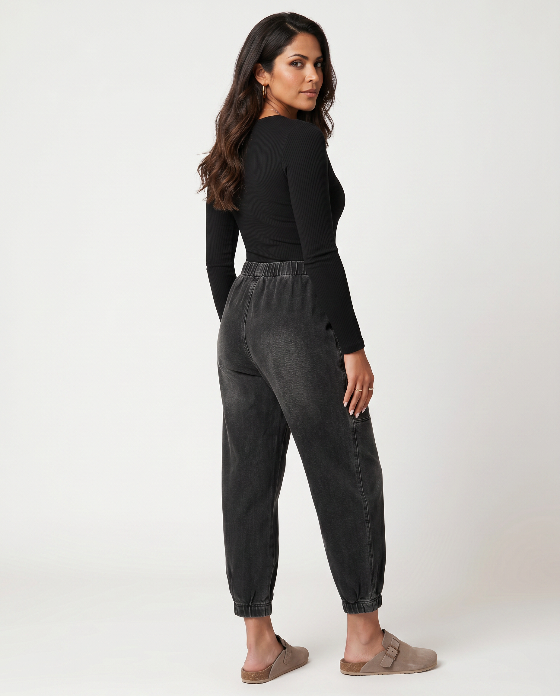 Black tapered denim jeans with elastic waist, side seam stitching, and cuffed ankles