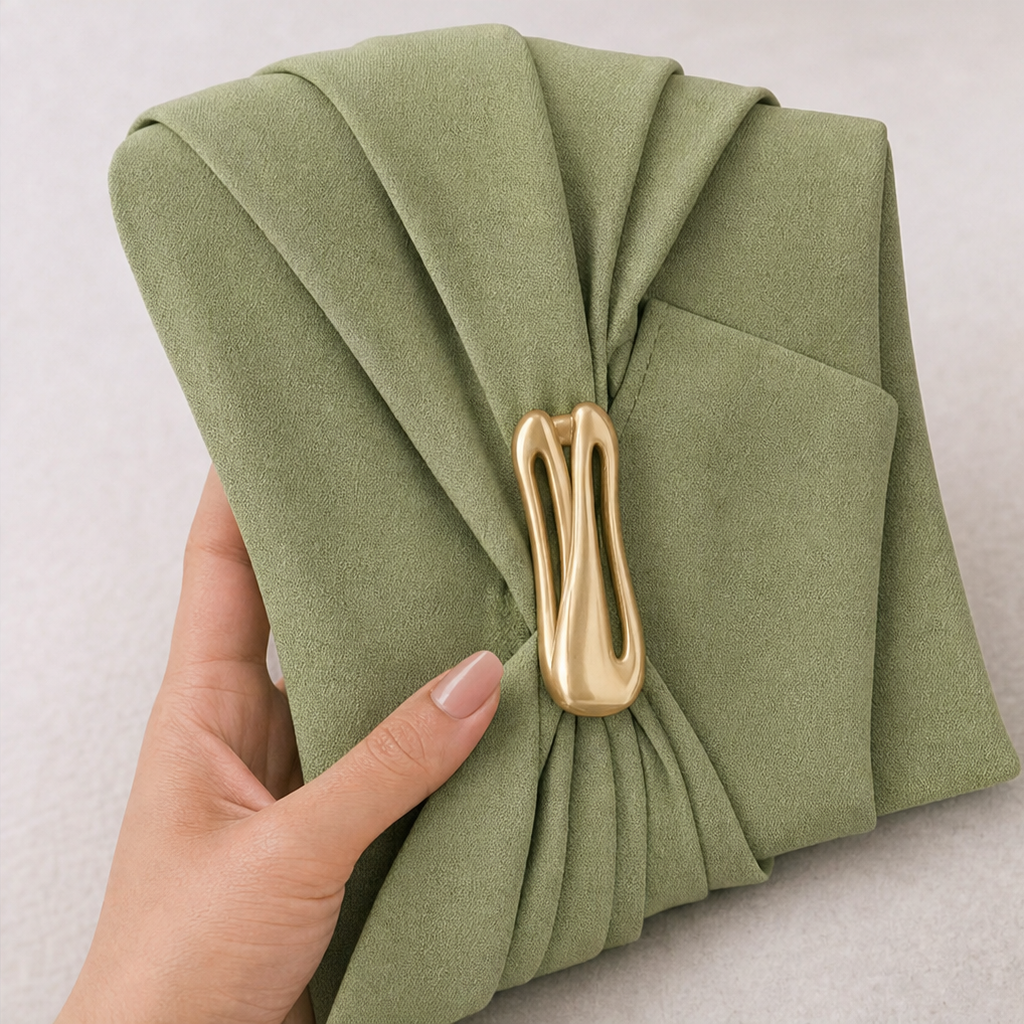 Close-up of sage green fabric with gold-tone twisted buckle waist hardware