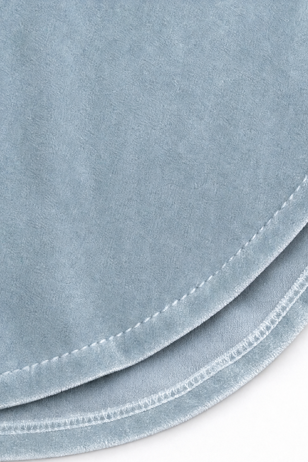Close-up of the curved stitched hem on a light blue velvet blouse