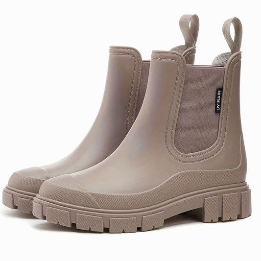 Beige chelsea boots side view with elastic gore, pull tabs, and thick tread block heel