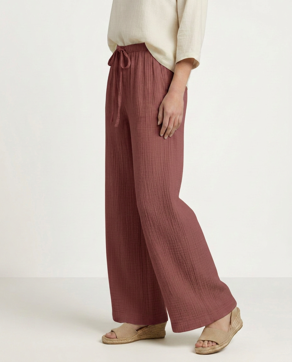 Wide-leg trousers with elastic waist and drawstring, dusty rose textured fabric, side view.
