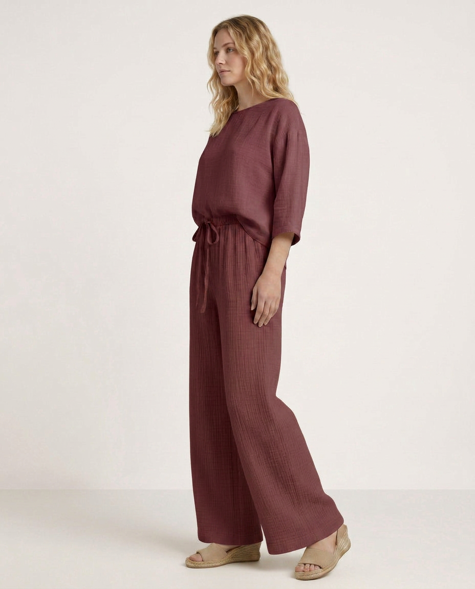 Wide-leg trousers with elastic waist and drawstring, burgundy textured fabric, side view.